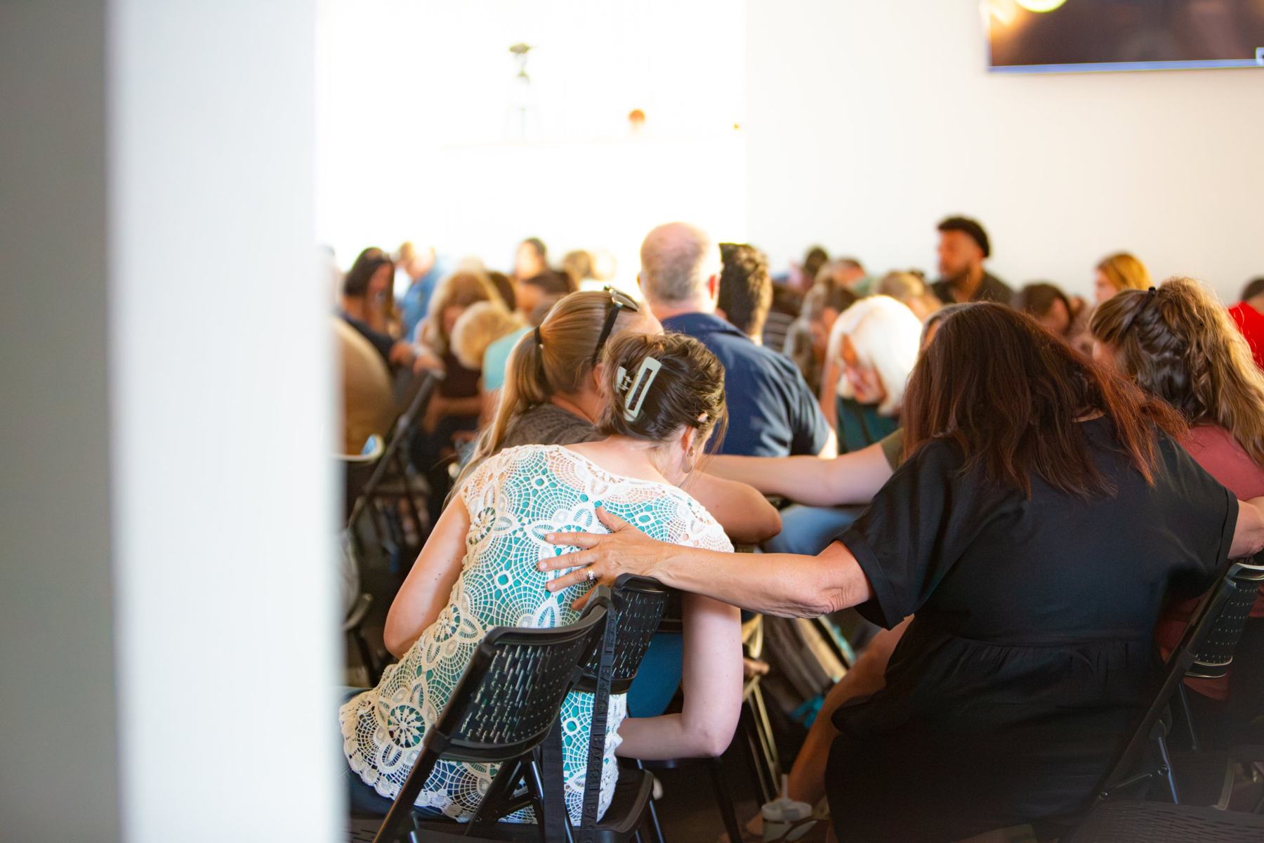 People praying together with hands on shoulders